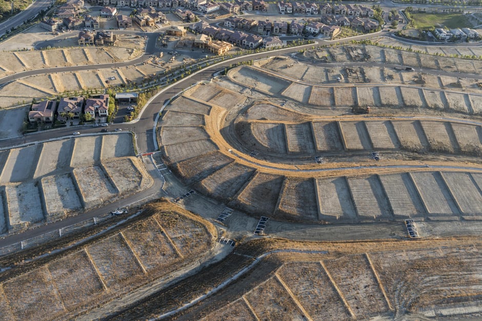 Aerial view of a residential homebuilding community showing developed homes, active construction, and finished lots.